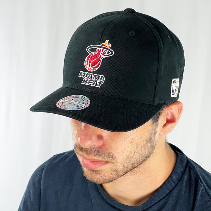 Support the NBA Miami Heat basketball team with this low profile snapback cap. Finished in black and paired with a curved visor, the fitted crow features the iconic Miami Heat logo fully fitted for your complete comfort in a range of sizes. Mitchell & Ness embroidery to rear Colour: Black Brand New with Tags - Size on Tag: One Size