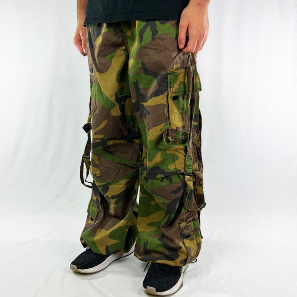 Super cute Youth Deadstock Vintage Criminal Damage parachute cargo trousers in camouflage military khaki style with Criminal Damage embroidered logo. Cord to waist. Plenty of pockets to sides and back. Lattice carnaby style. Adjustable cord to hem. Due to age you may need to tie the pull cord to keep in place Material: Polyester/Cotton Condition: Brand new with tags Measurements:  - Size on Tag: Large Length: 43 Inches Inseam: 32 Inches Waist: Adjustable waist