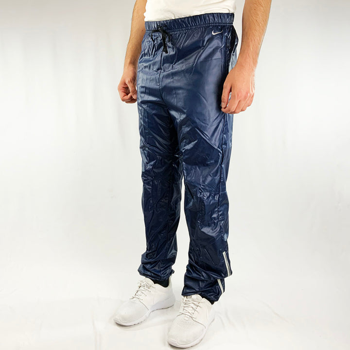 Y2k Deadstock Vintage Nike Teflon reflective joggers in navy blue with Nike swoosh to front. Pockets on side and rear. Adjustable drawstring on waist. Zip closure to hem with reflective outline. Condition: Brand new with tags  Colour: Navy Blue