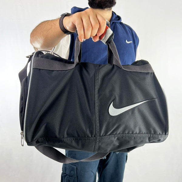Y2k Deadstock Vintage Nike Swoosh gym bag in black with large Nike swoosh. Plenty of room to keep your workout essentials. Zip pocket to keep your footwear so your clothes don't get dirty. Cool designed handle with velcro closure. Materials: Polyester/Nylon/Cotton  Colour: Black Brand New with Tags