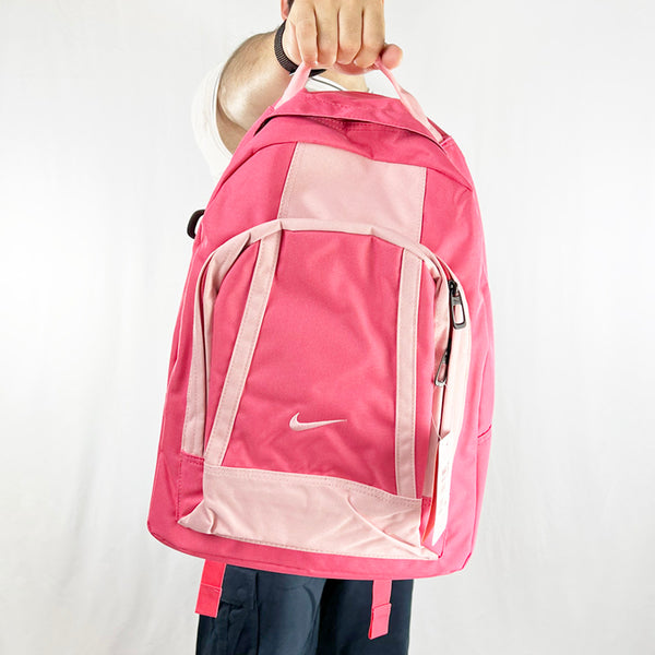 Y2k Deadstock Vintage Nike Swoosh backpack in pink with embroidered Nike swoosh. With its large laptop sleeve and roomy main compartment, this backpack is make to take you places. This backpack also has a front compartment. Unisex. Materials: Polyester/Nylon  Colour: Pink Brand New with Tags
