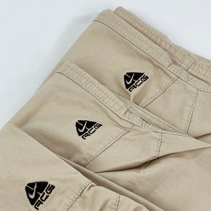 2007 Women's ﻿Deadstock Vintage Nike ACG Cargo Trousers in beige with Nike ACG embroidered logo to knee. Low rise trousers. Pockets to sides and back. Belt loops for belt adjustment. Material: Cotton  Condition: Brand new with tags