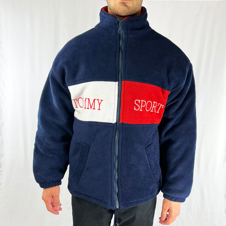 Vintage Tommy Sport oversized jacket in navy blue with full zip closure. Tommy Sport spellout to front and back. Fleece coating. Adjustable drawstring to hem. Colour: Navy Blue Condition: Excellent _ Size on Tag: Small Measurements: Pit to Pit: 22.5 Inches Length: 28 Inches