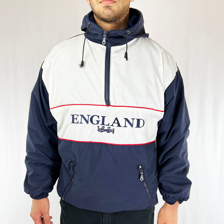England pullover fleeced hoodie in the iconic navy, white and red England international football team colours. England lions spellout logo to front. Adjustable cord to waist. Zip pockets to front. Adjustable string to hood. Fleeced inner layer. 1/2 Zip closure. Colour: Navy Condition: Good - Size on Tag: Small Pit to Pit: 23 Inches Length: 28.5 Inches