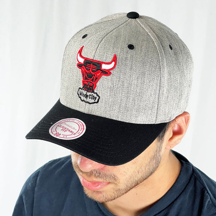 Support the NBA Chicago Bulls basketball team with this low profile snapback cap. Finished in grey and paired with a black curved visor, the fitted crow features the iconic Chicago bulls logo with the windy city spellout fully fitted for your complete comfort in a range of sizes. Mitchell & Ness embroidery to rear Colour: Grey Brand New with Tags - Size on Tag: One Size