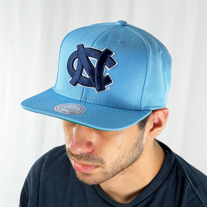 Support the NCAA North Carolina College Basketball team with this classic tall and proud blue snapback cap. Crafted with a high structured crown and fully fitted for your complete comfort in a range of sizes, it is finished with a flat visor and NC logo embroidery and Mitchell & Ness embroidery to rear Colour: Blue Brand New with Tags - Size on Tag: One Size