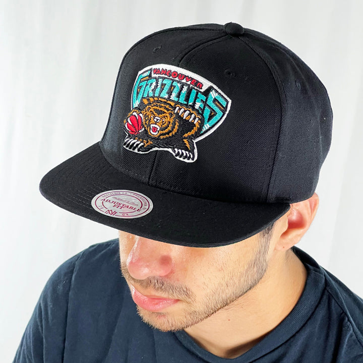 Support the NBA Vancouver Grizzlies basketball team with this low profile snapback cap. Finished in black and paired with a flat visor, the fitted crow features the iconic Vancouver Grizzlies logo fully fitted for your complete comfort in a range of sizes. Mitchell & Ness embroidery to rear Colour: Black Brand New with Tags - Size on Tag: One Size