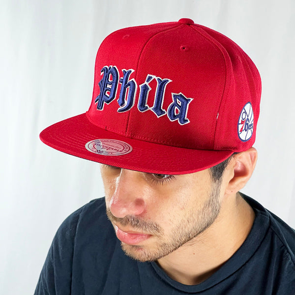 Support the Philadelphia 76ers with this classic tall and proud red snapback cap. Crafted with a high structured crown and fully fitted for your complete comfort in a range of sizes, it is finished with a flat visor and big, bold, 'PHILA' embroidery, 76ers logo embroidery on the left side and Mitchell & Ness embroidery to rear Colour: Red Brand New with Tags - Size on Tag: One Size