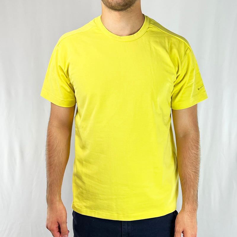 2003 Deadstock Vintage Nike Swoosh T-shirt in yellow. Embroidered Nike swoosh to sleeve. Short sleeve t-shirt with crewneck. Perfect for summer. Material: Cotton/Elastane Colour: Yellow Brand New with Tags _ Size on Tag: Large Measurements: Pit to Pit: 20.5 Inches Length: 27 Inches