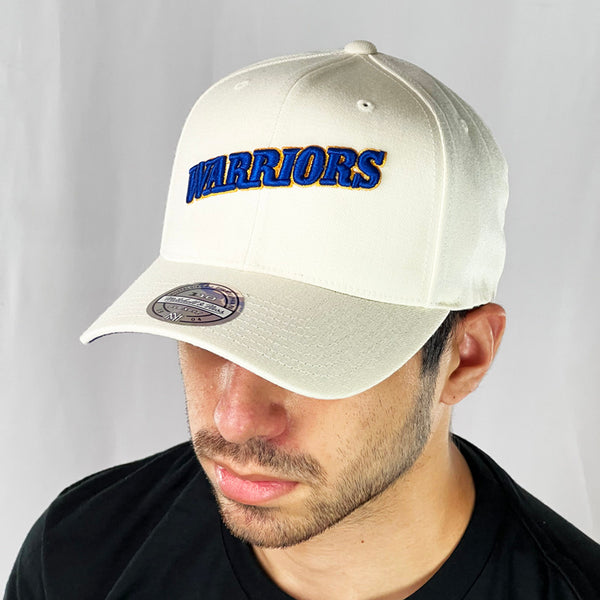Support the NBA Golden State Warriors basketball team with this low profile snapback cap. Finished in off white and paired with a curved visor, the fitted crow features the 'Warriors' spellout fully fitted for your complete comfort in a range of sizes. Mitchell & Ness embroidery to rear Colour: Off White Brand New with Tags - Size on Tag: One Size