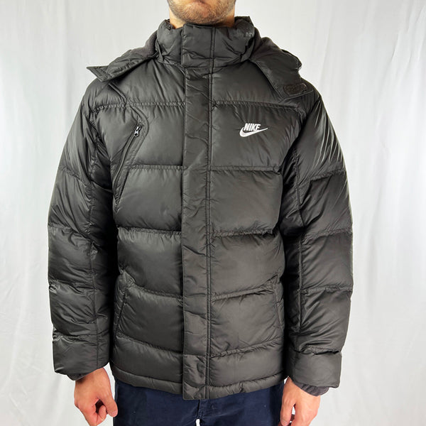 2008 Boys Deadstock Vintage Nike Puffer Jacket in Dark Brown. Nike Spellout logo to chest. Zip pockets to front. Removeable hood. Inner pocket. - Materials: Polyester  Fill: Duck Down - Colour: Dark Brown Brand New with Tags - Size on Tag: Boys XL (fits adult small) Measurements: Pit to Pit: 23 Inches Length: 26.5 Inches