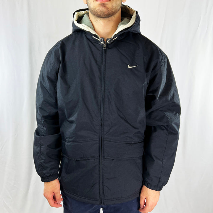 Y2K Deadstock Vintage Nike Fleeced Jacket in Black. Embroidered Nike Swoosh to chest. Adjustable cord on hood. Pockets to front and inner zip pocket. Adjustable cord to waist. Zip closure Jacket. - Materials: Body: Nylon Lining: Polyester Trim: Cotton