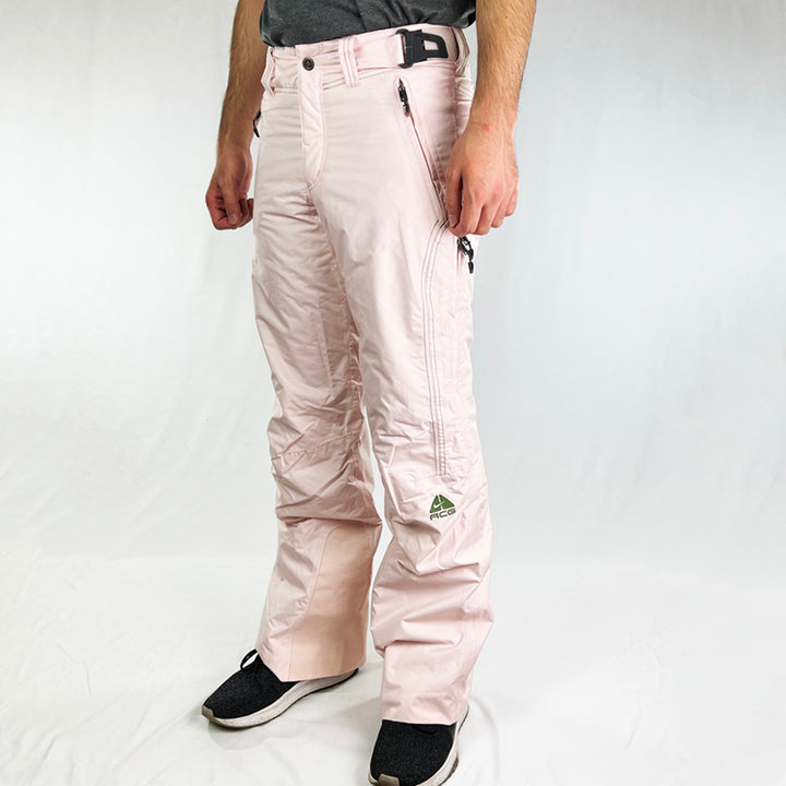 Y2K Women's Deadstock Vintage Nike ACG Cargo Ski Pants in baby pink with Nike ACG branding. Storm-Fit 5 technology, cargo trousers look with plenty of pockets. Fleeced inner layer. Boot gaiters. Belt loops for belt adjustment. - Materials: Nylon/Polyester - Colour: Pink Brand New with Tags
