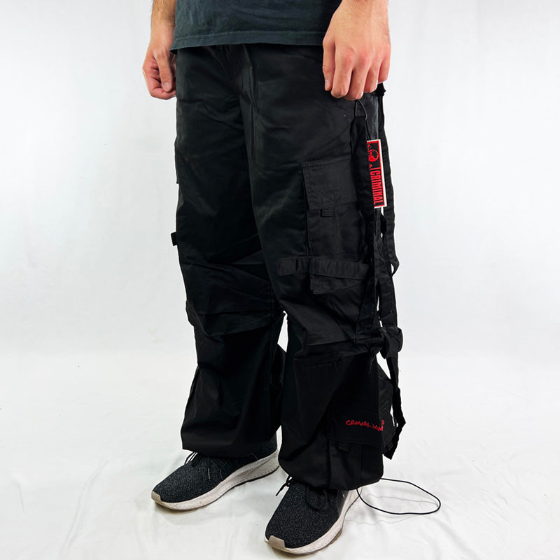 Super cute Youth Deadstock Vintage Criminal Damage parachute cargo trousers in black with Criminal Damage embroidered logo. Cord to waist. Plenty of pockets to sides and back. Lattice carnaby style. Adjustable cord to hem. Due to age you may need to tie the pull cord to keep in place Material: Polyester/Cotton Condition: Brand new with tags Measurements:  - Size on Tag: Small Length: 42 Inches Inseam: 31 Inches Waist: Adjustable waist