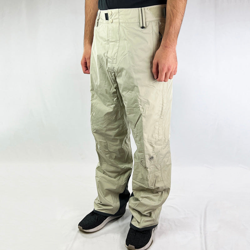 Y2K Deadstock Vintage Nike ACG Cargo Ski Pants in cream with Nike ACG branding. Storm Fit 5 technology to keep you comfortable and dry in rain, sleet, and snow. The seam sealed, breathable fabric completely blocks wind and rain penetration at 5,000mm of water pressure. Cargo trousers style. Plenty of pockets. Boot gaiters. Belt loops for belt adjustment. - Materials: Body: 100% Nylon Fill: 100% Polyester