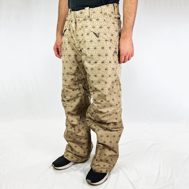 Y2K Women's Deadstock Vintage Nike ACG Cargo Ski Pants in beige with Nike ACG branding. Storm-Fit technology. Thermore light insulation fleeced inner layer. Zip pockets to sides and inner thigh. Boot gaiters. Belt loops for belt adjustment. - Materials:  Body: Polyester Fill: Polyester - Colour: Beige Brand New with Tags