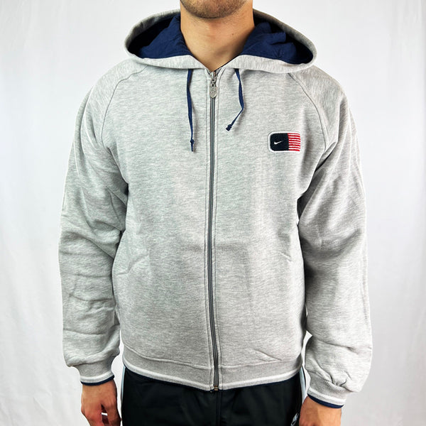 Y2K Deadstock Vintage Nike USA hoodie in grey with the Nike USA logo to chest. USA spellout to back. Pockets to front. Hood with adjustable drawstrings. Full zip closure. Comfortable and cosy. - Materials: 75% Cotton - 22% Polyester - 3% Acrylic - Colour: Grey Brand New with Tags