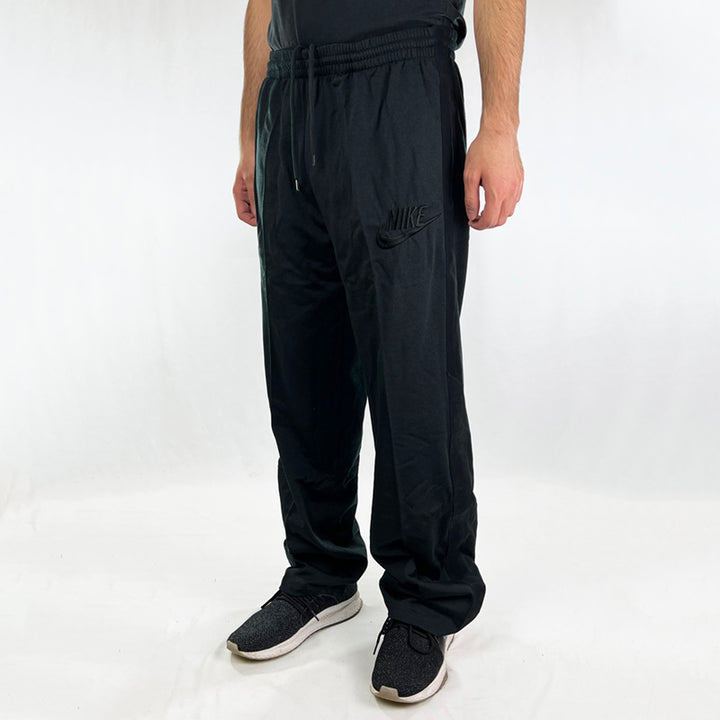 Y2K Deadstock Vintage Nike iceman joggers in black. These joggers are from the George Gervin NBA player who rose to stardom as a member of the San Antonio Spurs in the 1970s. Embroidered Nike spellout logo to front. Pockets to sides. Suede sides. Adjustable drawstrings to waist.  - Materials: 50% Cotton - 50% Polyester - Colour: Black Brand New with Tags