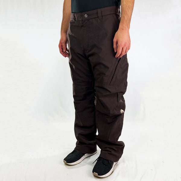 Y2K Deadstock Vintage Nike ACG cargo trousers in brown with Nike ACG branding. Thermore light insulation fleeced inner layer. Zip pockets. Belt loops for waist adjustment. - Materials: Polyester - Colour: Brown Brand New with Tags