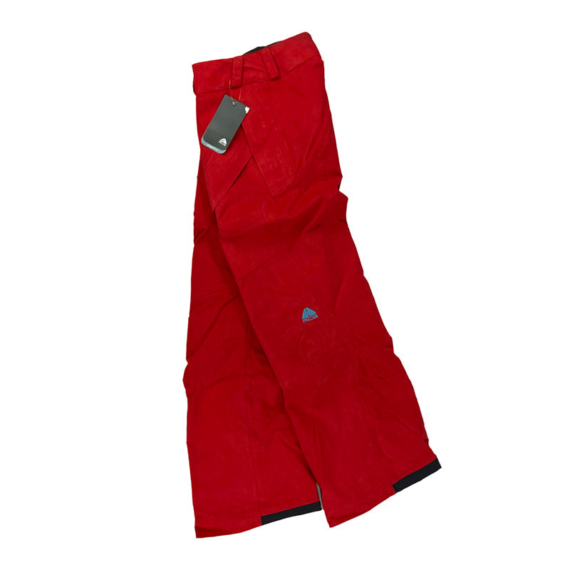 Y2K Women's Deadstock Vintage Nike ACG Cargo Ski Pants in red with Nike ACG branding. Storm Fit 5 technology to keep you comfortable and dry in rain, sleet, and snow. Fleeced inner layer. Zip pockets. Boot gaiters. Belt loops for belt adjustment. Suede style. - Materials: Polyester - Colour: Red Brand New with Tags