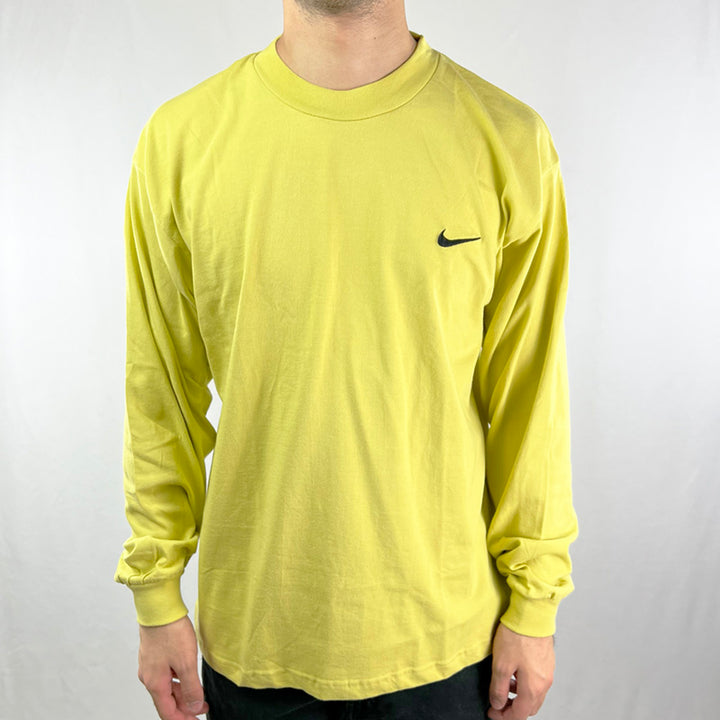 90s Deadstock Vintage Nike long sleeve top in yellow with embroidered Nike swoosh to chest. Crew neck. - Materials: 100% Cotton - Colour: Yellow Brand New with Tags - Size on Tag: Medium Measurements: Pit to Pit: 22 Inches Length: 28 Inches