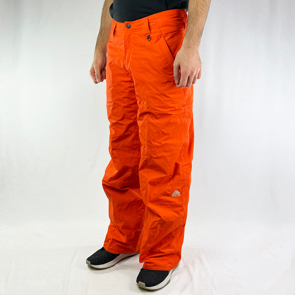 Y2K Women's Deadstock Vintage Nike ACG Ski Pants in Orange with Nike ACG branding. Clima-Fit technology. Funky design. Fleeced inner layer. Zip pockets to sides. Boot gaiters. Belt loops for belt adjustment. - Materials: Nylon/Polyester - Colour: Orange Brand New with Tags