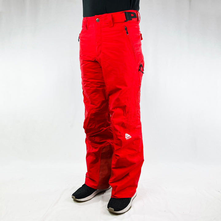 Y2K Women's Deadstock Vintage Nike ACG Cargo Ski Pants in red with Nike ACG branding. Storm Fit 5 technology to keep you comfortable and dry in rain, sleet, and snow. Fleeced inner layer. Zip pockets. Boot gaiters. Belt loops for belt adjustment. - Materials:  Body: Nylon Fill: Polyester