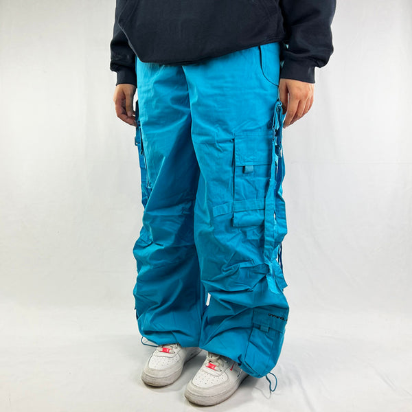 Deadstock Vintage Criminal Damage parachute cargo trousers in blue with Criminal Damage embroidered logo. Cord to waist. Plenty of pockets to sides and back. Carnaby style. Adjustable cord to hem. Due to age you may need to tie the pull cord to keep in place Material: Polyester/Cotton Condition: Brand new with tags Measurements: