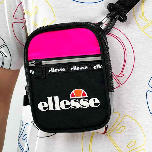 Ellesse Aquino small cross body bag in black and pink. Reflective strip to zip. The perfect way to style up any outfit, this crossbody bag has an all the way zip compartment. Logo across front. - Colour: Black Brand New with Tag - Materials: Shell: 90% Polyester - 10% Nylon Lining: 100% Polyester