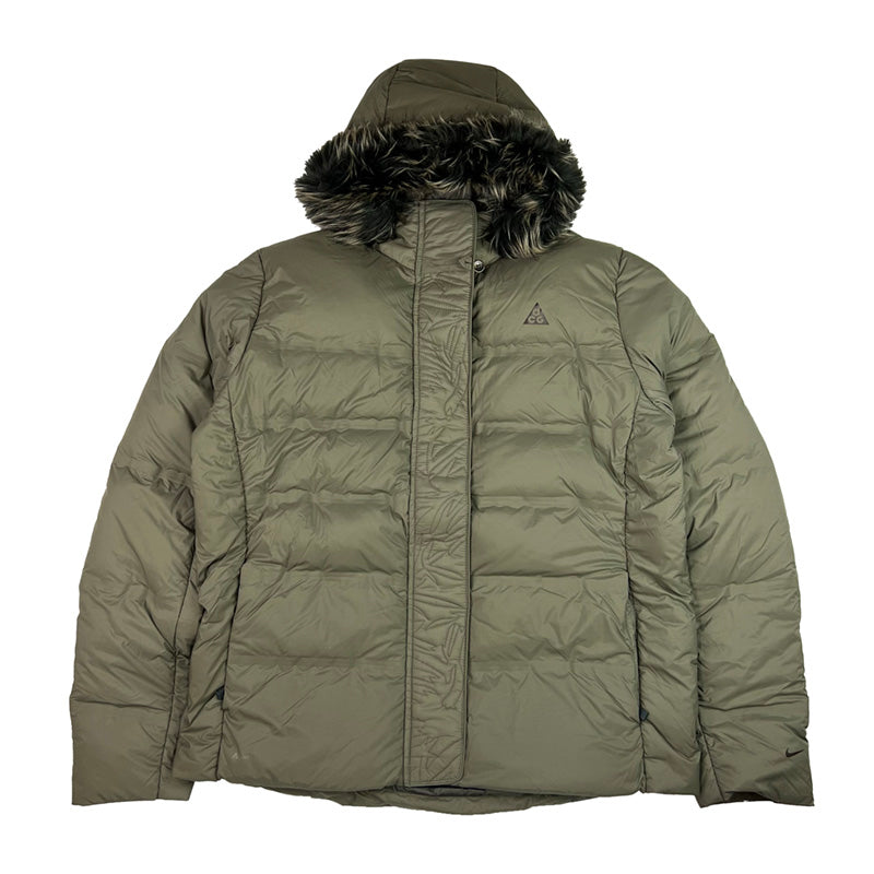 2009 Women's Deadstock Vintage Nike ACG Puffer Jacket in Khaki. Nike ACG logo to chest and swoosh to sleeve. Adjustable cord to hood. Fur on hood. Zip closure. Pockets to front. Adjustable cord to waist. 