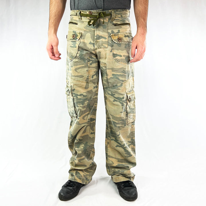 Deadstock Vintage Criminal Damage Jail Cargo Trousers in Camo with Criminal Damage branding. Plenty of pockets. Belt loops and adjustable drawstring to waist. Utility. Condition: Brand new with tags