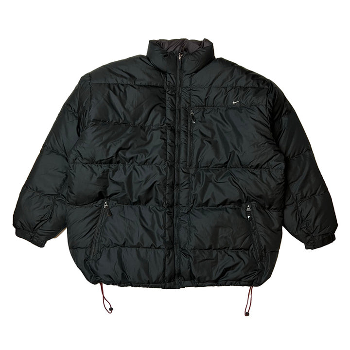 Y2K Deadstock Vintage Nike swoosh puffer jacket in black. Embroidered Nike swoosh to chest. Zip pockets to front. Zip closure to jacket. Adjustable cord to waist. - Materials: Body: Polyester Fill: Down - Colour: Black Brand New with Tags - Size on Tag: XXL Measurements: Pit to Pit: 32 Inches Length: 33 Inches