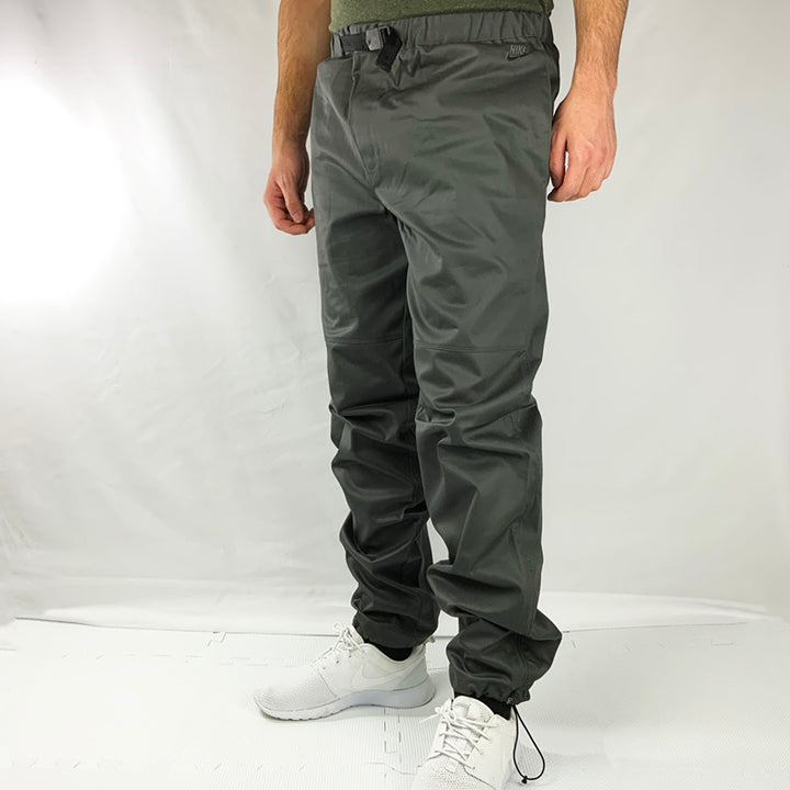 2008 Deadstock Vintage Nike Trousers in Grey with embroidered swoosh and spellout logo to side of waist. Adjustable waist and adjustable tension to ankle. Water repellent feature. Colour: Grey Brand New with Tags Size on Tag: Medium MEASUREMENTS: Inseam: 31.5 INCHES Length: 41.5 INCHES Waist: GB 31/33 All our items are of vintage conditions. This means some items may show signs of minor wear. Any major defects will be pictured and stated in the description