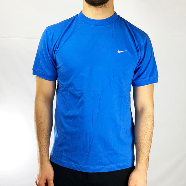 2004 Boys Deadstock Vintage Nike T-shirt in Blue is perfect fit for adult small. Embroidered Nike swoosh branding to chest.  Colour: Blue  Brand New with Tags  Size on Tag: Boys XL (fits adult small) Pit to Pit: 19.5 inches  Length: 26 inches  All our items are of vintage conditions. This means some items may show signs of minor wear. Any major defects will be pictured and stated in the description