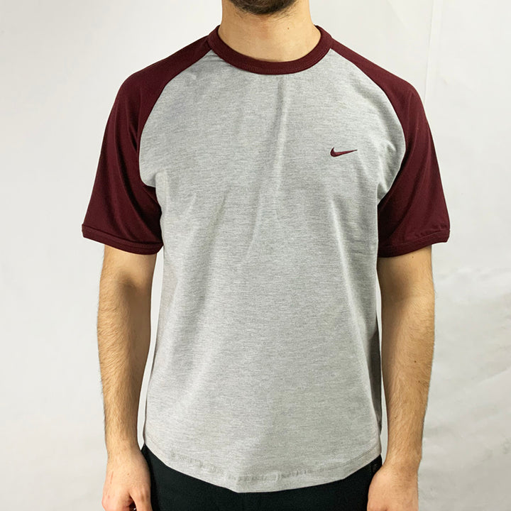 2004 Deadstock Vintage Nike Swoosh T-shirt in Grey with Nike swoosh to chest and burgundy sleeve. Colour: Grey Brand New with Tags _ Size on Tag: Medium Measurements:  Pit to Pit: 20.5 Inches Length: 26.5 Inches  All our items are of vintage conditions. This means some items may show signs of minor wear. Any major defects will be pictured and stated in the description