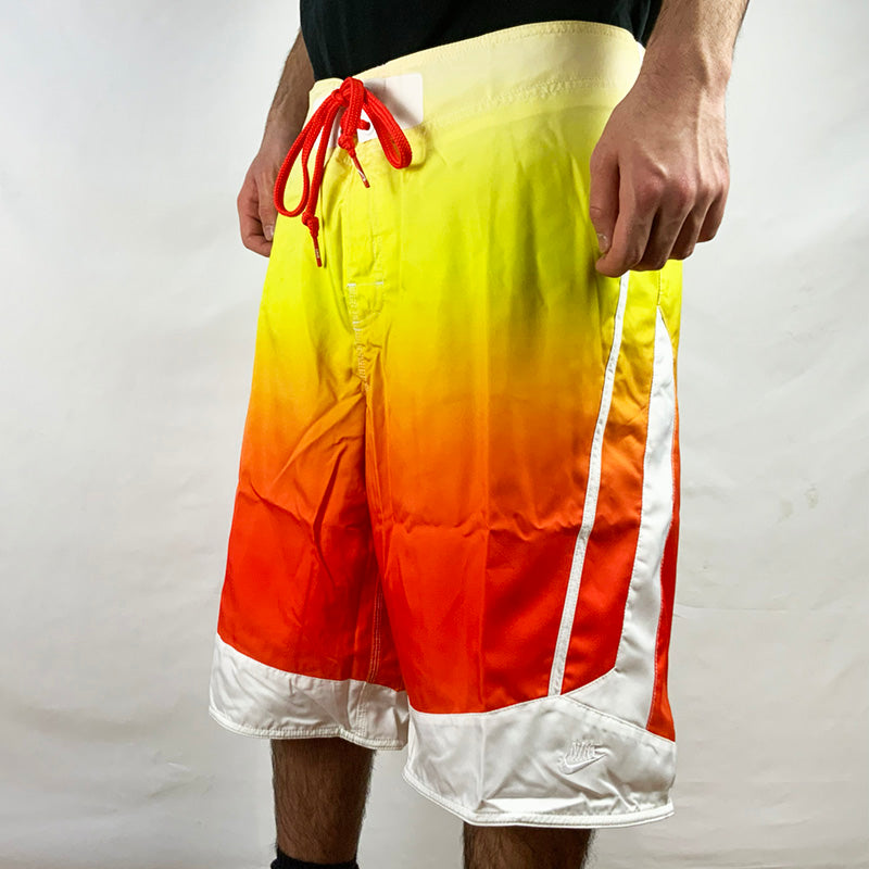 2008 Deadstock Vintage Nike Sportswear Shorts in Multicoloured - Yellow / Orange / White. Embroidered Nike branding to side. Adjustable drawstrings to waist. Pockets to side. Colour: Multicoloured  Brand New with Tags  -  Size on Tag: 34  Measurements:  Length: 24 Inches  Waist: GB 34 Adjustable drawstrings  All our items are of vintage conditions. This means some items may show signs of minor wear. Any major defects will be pictured and stated in the description