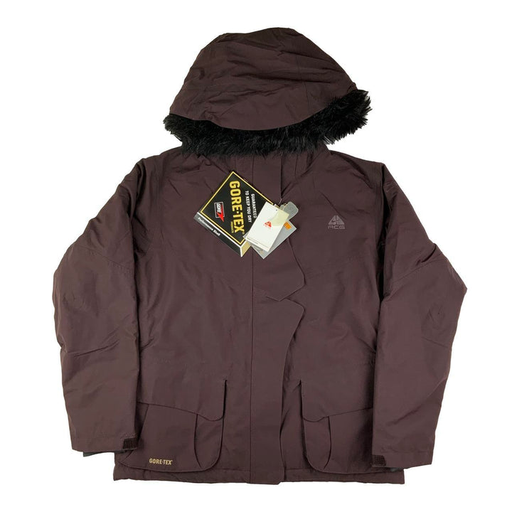 2007 Women's Deadstock Vintage Nike ACG Gore-Tex Jacket in Brown. Nike ACG logo to chest and shoulder. Gore-Tex spellout to pocket. Zip closure. Removable hood with removeable fur. Cord to adjust hood. Pockets to front, under arms and inner pockets. Fleeced inner layer. Adjustable cord to waist. 